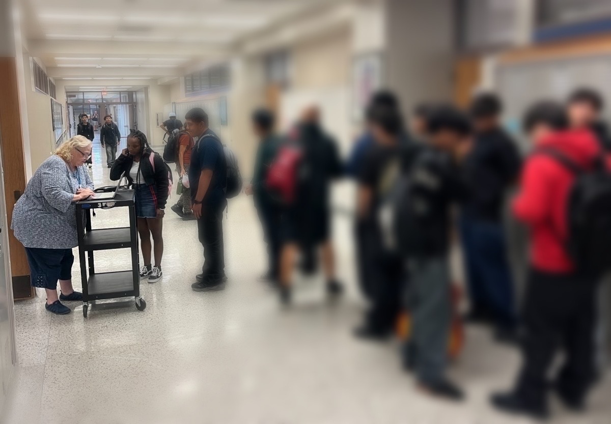 Curriculum specialist Stacy Stambaugh issues tardy passes in the third floor hallway.